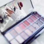 Close-up of makeup brushes in a decorative holder and a colorful eyeshadow palette.